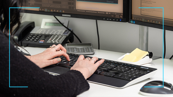 woman at her table typing on her keyboard